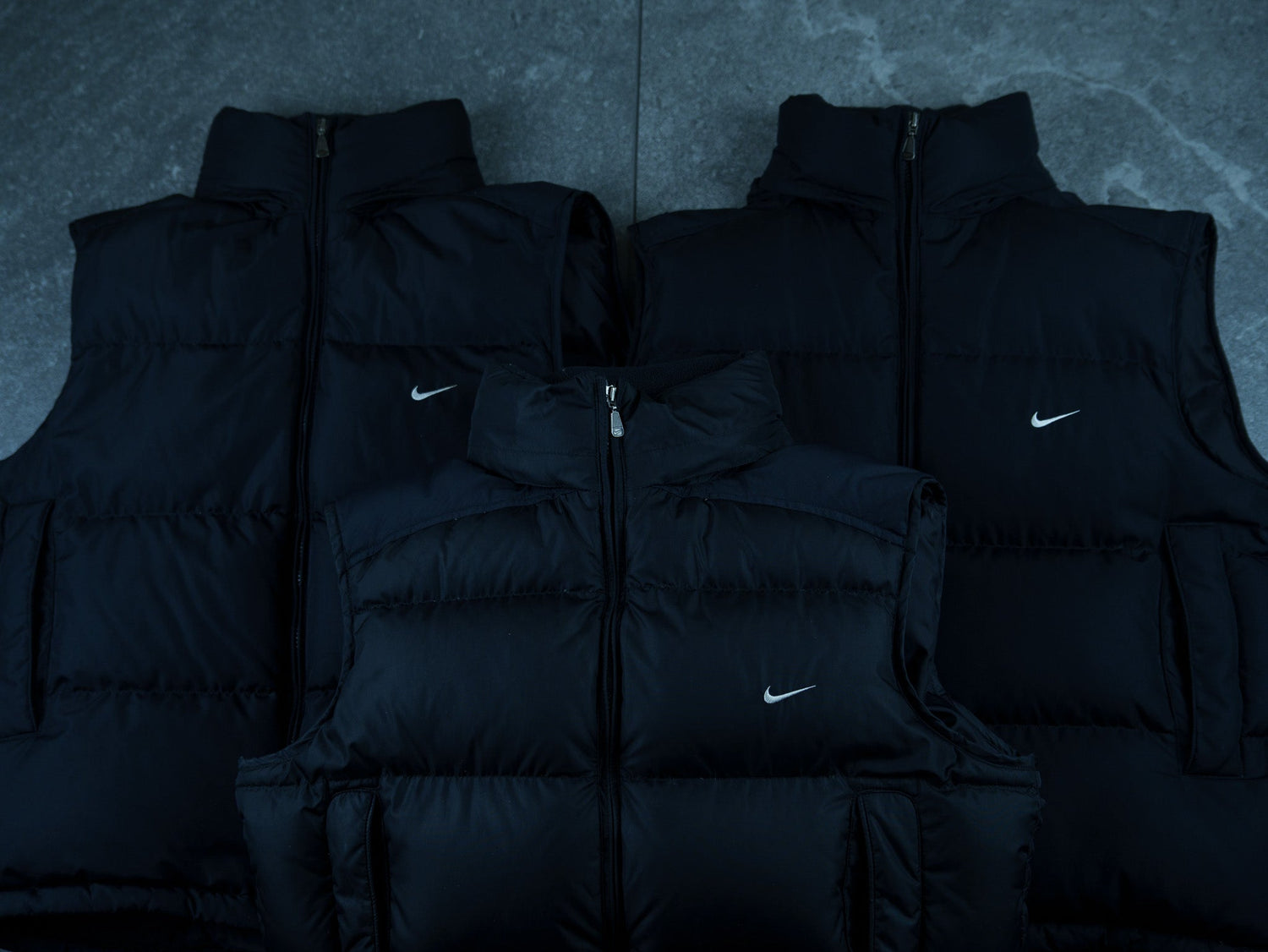 Vintage Nike puffer jackets displayed on a gray surface, part of the exclusive Atelier Solitaire collection, featuring iconic streetwear with timeless style.